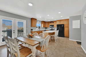 Dining area featuring light tile patterned floors, recessed lighting, a textured ceiling, and french doors