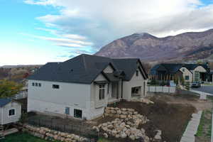 View of side of property featuring a fenced backyard, roof with shingles, and a mountain view