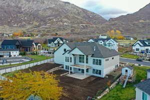Rear view of house featuring a patio area, a mountain view, an outbuilding, and a residential view