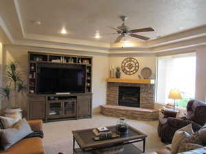 Living room with, a ceiling fan, a stone fireplace, carpet floors, and recessed lighting