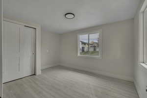 Unfurnished bedroom featuring light wood-type flooring and a closet