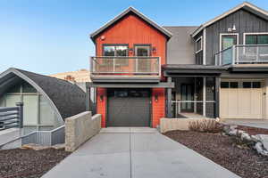 View of front of house featuring a balcony, board and batten siding, an attached garage, and concrete driveway