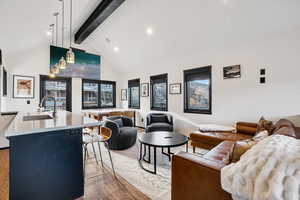 Living area with beam ceiling, light wood-style flooring, high vaulted ceiling, and recessed lighting