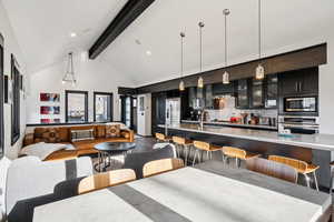 Dining area with beamed ceiling, high vaulted ceiling, and dark wood-style floors