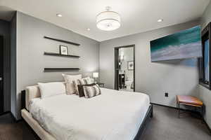 Bedroom with recessed lighting, ensuite bathroom, and dark colored carpet