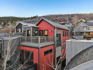 Back of property with board and batten siding, a residential view, a metal roof, and a balcony