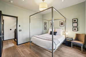 Bedroom with wood finished floors, recessed lighting, and a closet