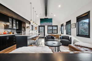 Living area with beam ceiling, high vaulted ceiling, recessed lighting, and light wood-type flooring