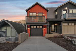 View of front of home with a balcony, board and batten siding, driveway, and a garage