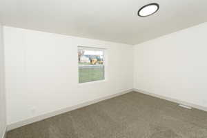 Carpeted empty room featuring a textured ceiling and baseboards