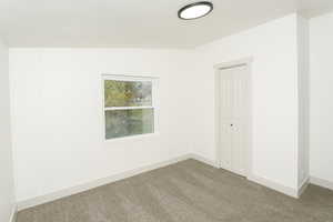 Spare room featuring carpet and baseboards