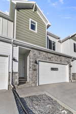 View of front facade featuring stone siding, concrete driveway, and an attached garage