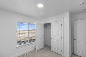 Unfurnished bedroom with light carpet and a closet