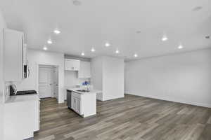 Kitchen with an island with sink, white cabinetry, recessed lighting, light wood-style flooring, and stainless steel appliances