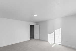 Empty room featuring light colored carpet and baseboards