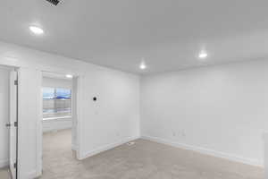 Empty room with light carpet and recessed lighting