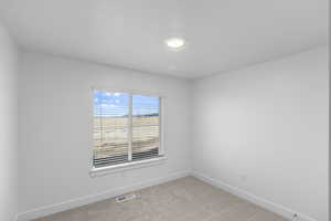 Spare room featuring light colored carpet and baseboards