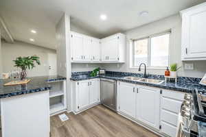 Kitchen featuring white cabinetry, appliances with stainless steel finishes, vaulted ceiling, light wood-style flooring, and recessed lighting