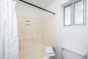 Bathroom featuring toilet and shower / bath combo with shower curtain
