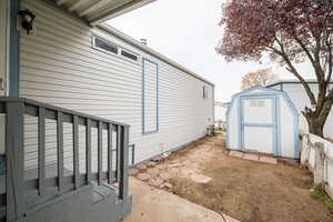 View of side of property featuring a storage shed and a patio area