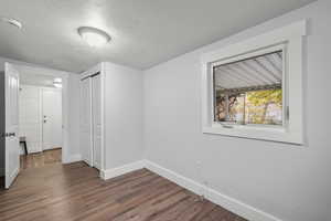 Unfurnished bedroom with a textured ceiling, dark wood-style flooring, and a closet