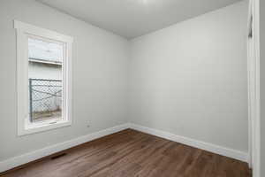Empty room with baseboards and dark wood-style flooring