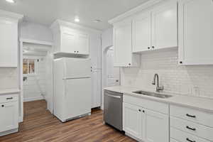 Kitchen featuring backsplash, freestanding refrigerator, white cabinetry, dark wood-style flooring, and light stone counters