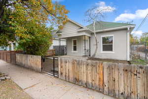 View of front of property featuring a fenced front yard, brick siding, a shingled roof, and a patio area