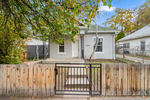 View of front of house featuring brick siding, a fenced front yard, a patio area, a gate, and a shingled roof