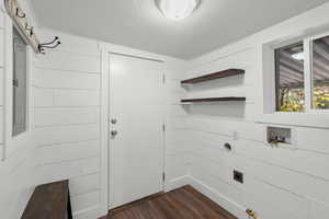 Laundry room with dark wood-type flooring, washer hookup, electric dryer hookup, and wooden walls