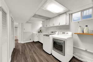 Laundry area with dark wood-style flooring, washing machine and clothes dryer, and cabinet space