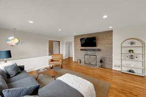 Living room featuring light wood finished floors, recessed lighting, and a stone fireplace