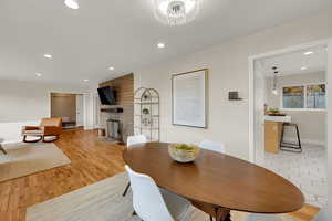 Dining area with recessed lighting, a stone fireplace, and light wood finished floors