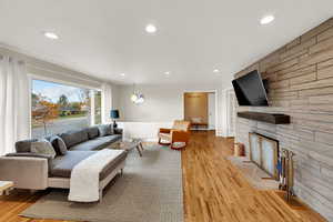 Living room featuring recessed lighting, light wood-type flooring, and a fireplace