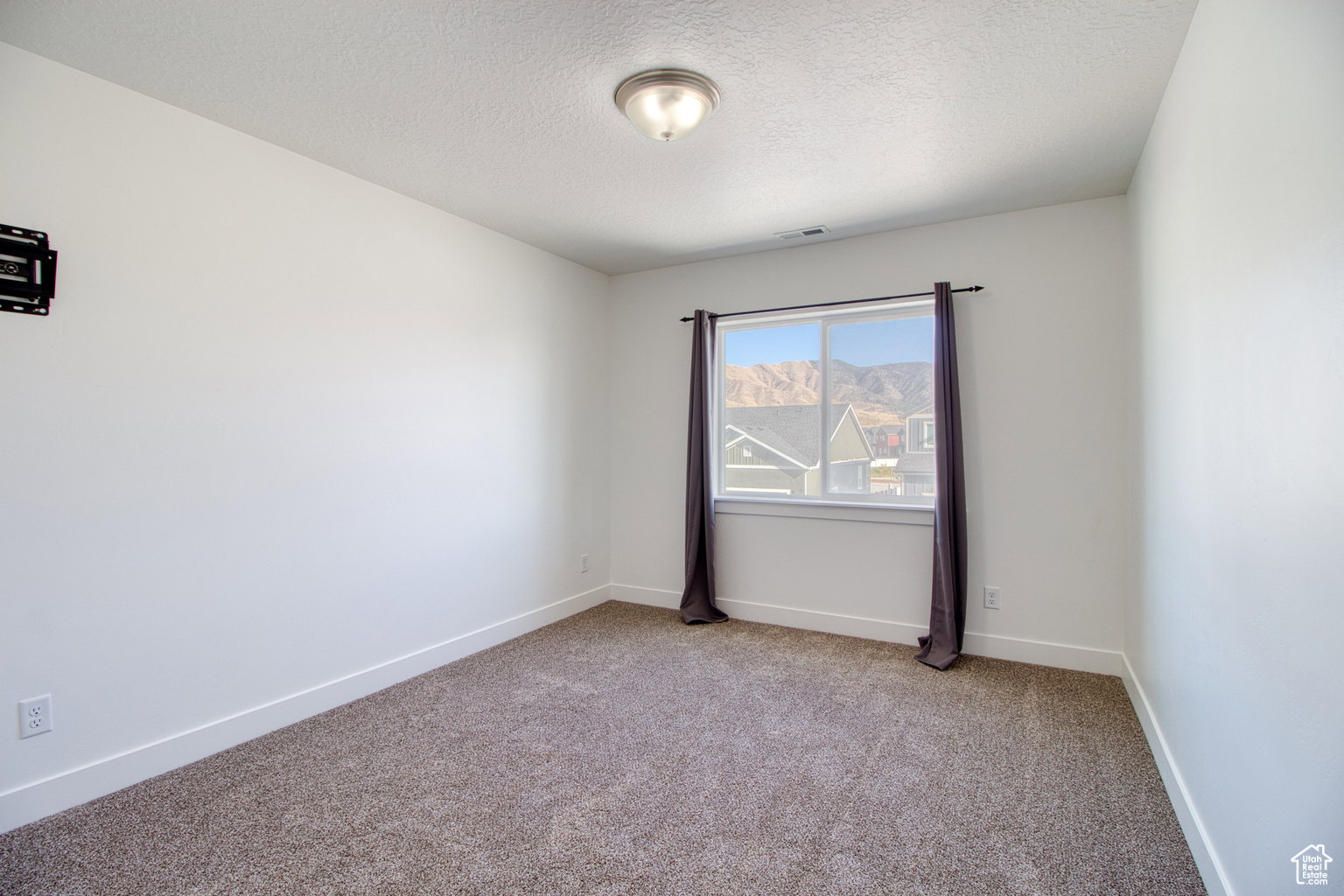 Carpeted empty room with baseboards and a textured ceiling