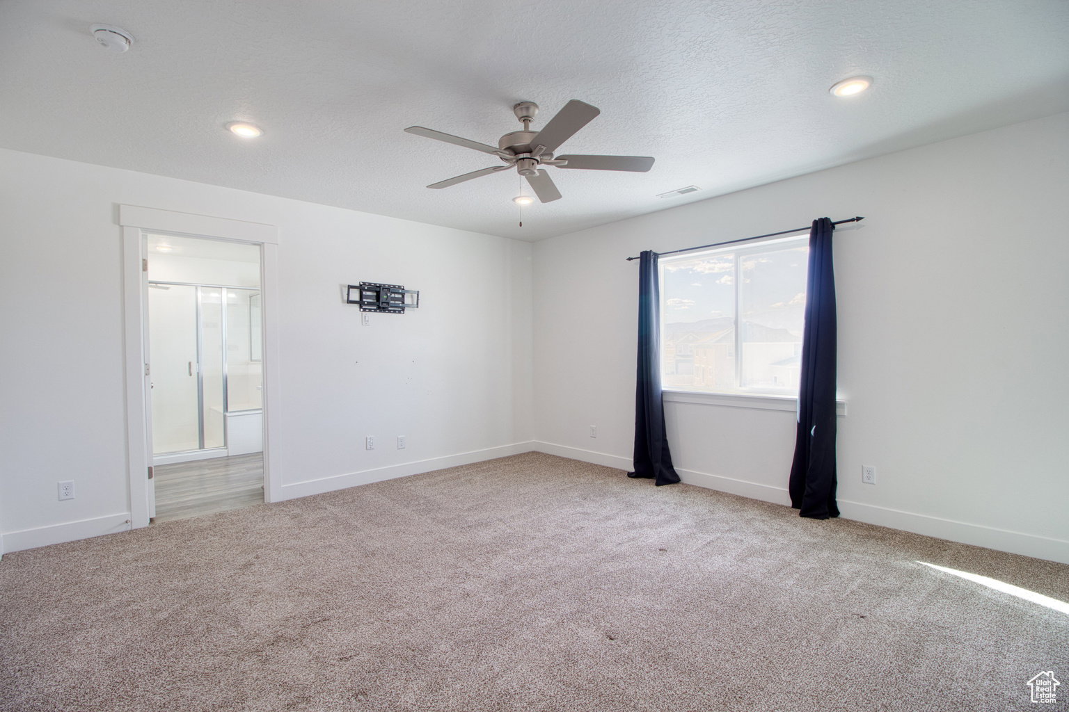 Unfurnished room with light carpet, a ceiling fan, and a textured ceiling