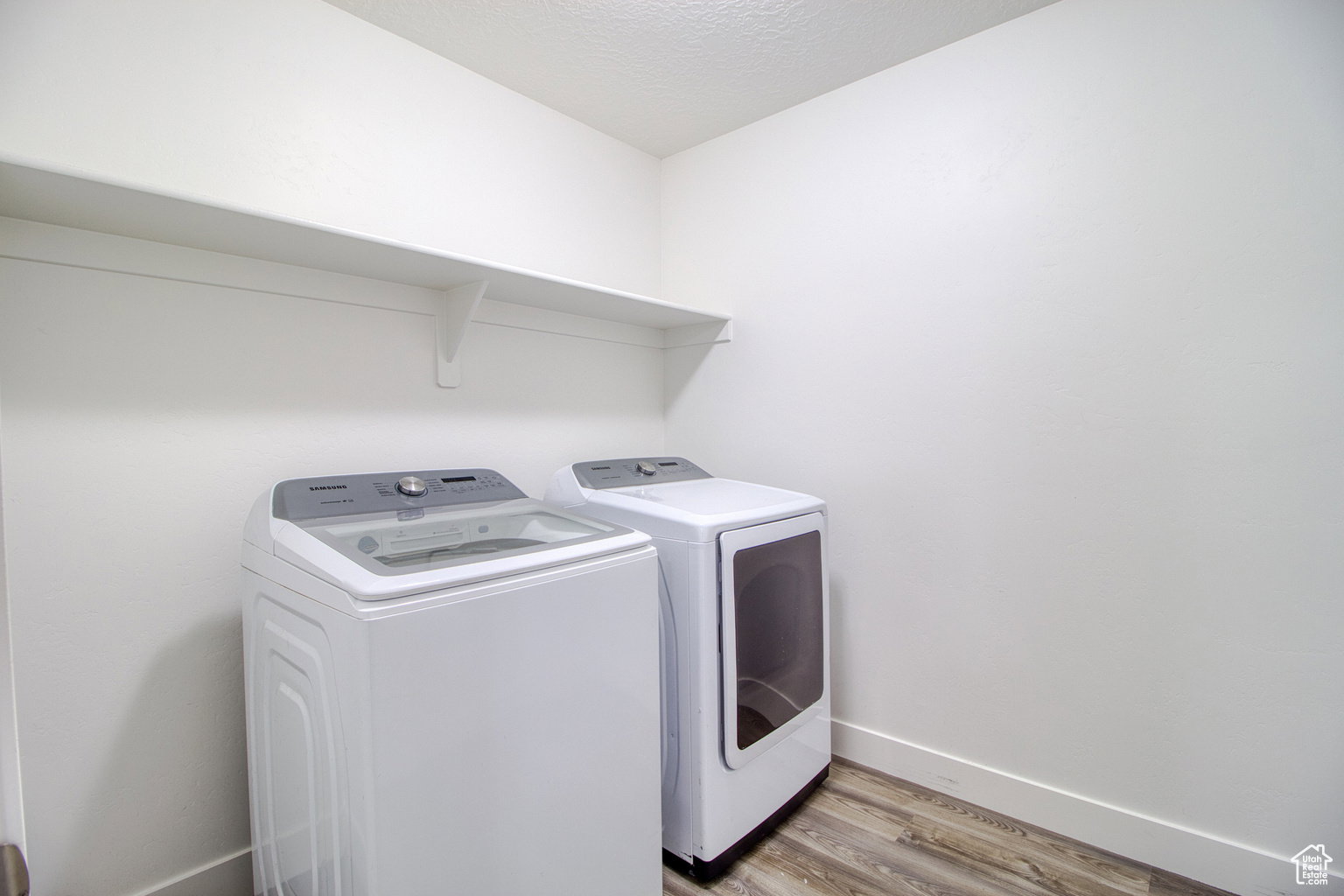 Washroom featuring light wood-style flooring, washing machine and dryer, and a textured ceiling