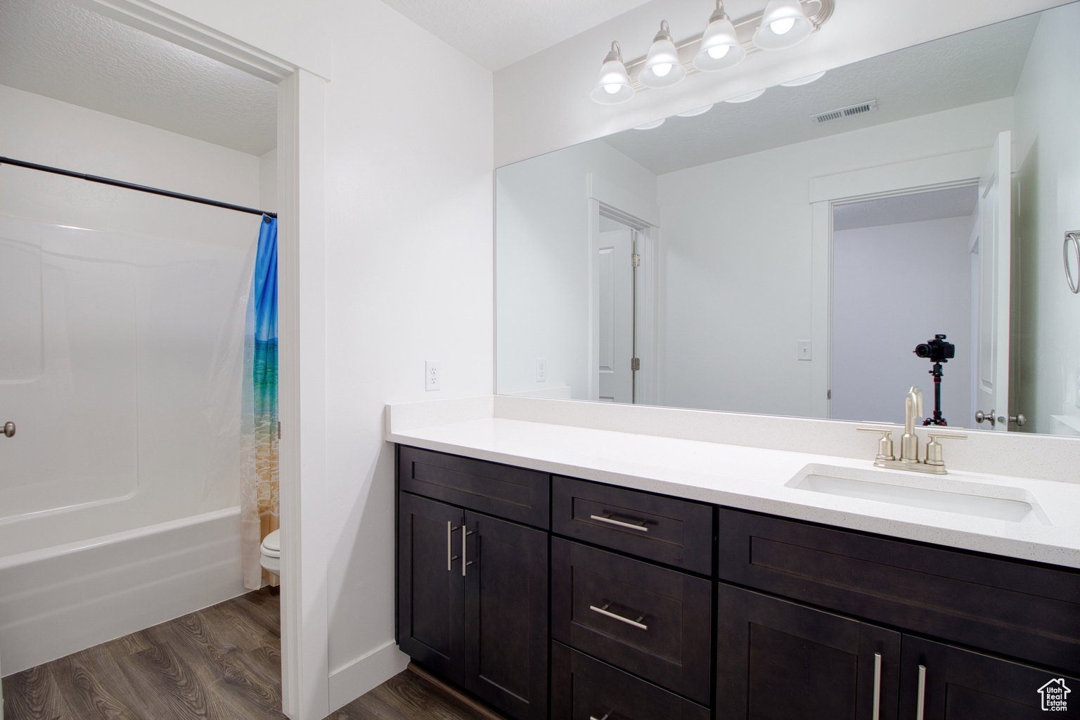 Full bath with vanity, dark wood finished floors, and shower / bath combo