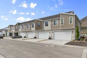 View of front of property with board and batten siding, a residential view, stone siding, driveway, and a garage