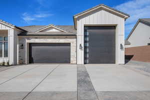 View of front of home with a garage, board and batten siding, a tile roof, and stone siding