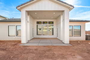 Rear view of property featuring a patio, board and batten siding, and a tiled roof