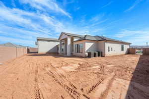 Rear view of house with a fenced backyard and stucco siding