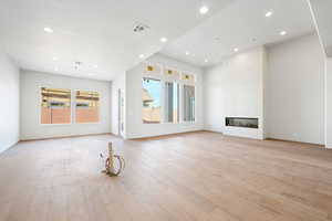 Unfurnished living room featuring light wood-style floors, recessed lighting, and a high end fireplace