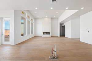 Unfurnished living room featuring light wood-style floors, recessed lighting, and a large fireplace