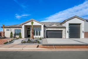 View of front facade with stone siding, a garage, driveway, and board and batten siding