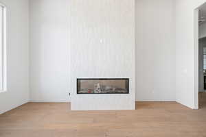 Unfurnished living room featuring a glass covered fireplace and wood finished floors