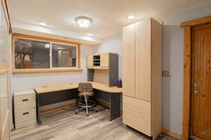 Office area featuring light wood-type flooring, recessed lighting, and built in desk