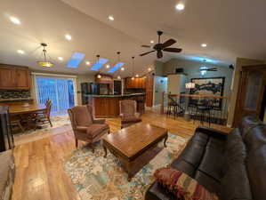 Living area featuring light wood-style floors, lofted ceiling, a skylight, recessed lighting, and a ceiling fan