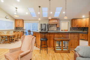 Kitchen with tasteful backsplash, hanging light fixtures, a skylight, a kitchen breakfast bar, and recessed lighting