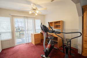 Workout area featuring ceiling fan, wainscoting, and dark colored carpet